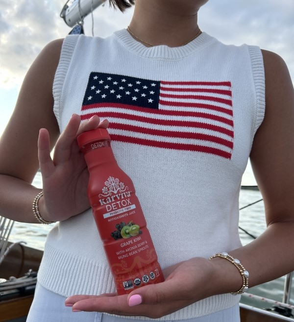 A woman holding the Karviva Detox, Grape Kiwi prebiotic fibre bottle.