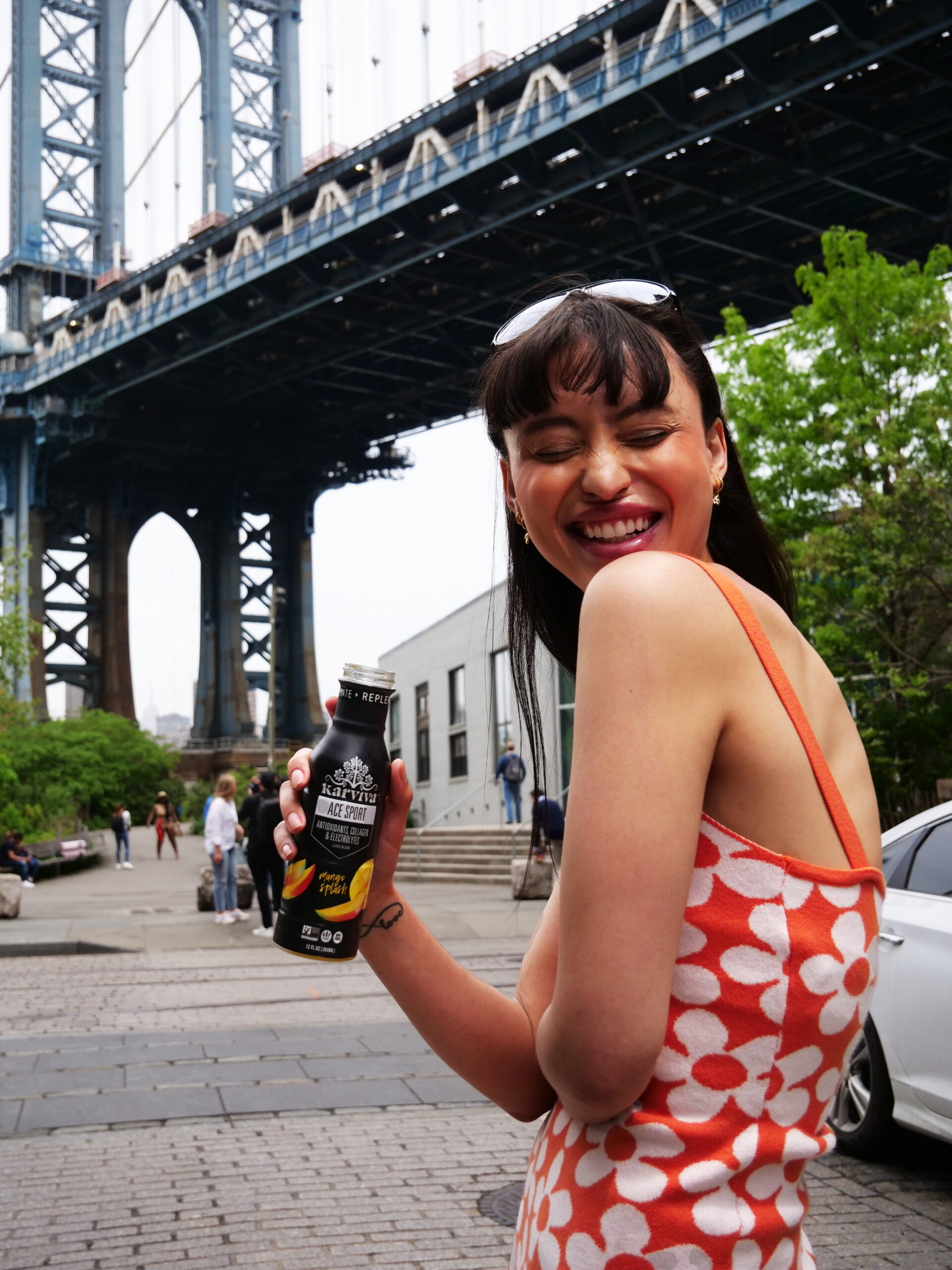 Woman holding beverage under city bridge