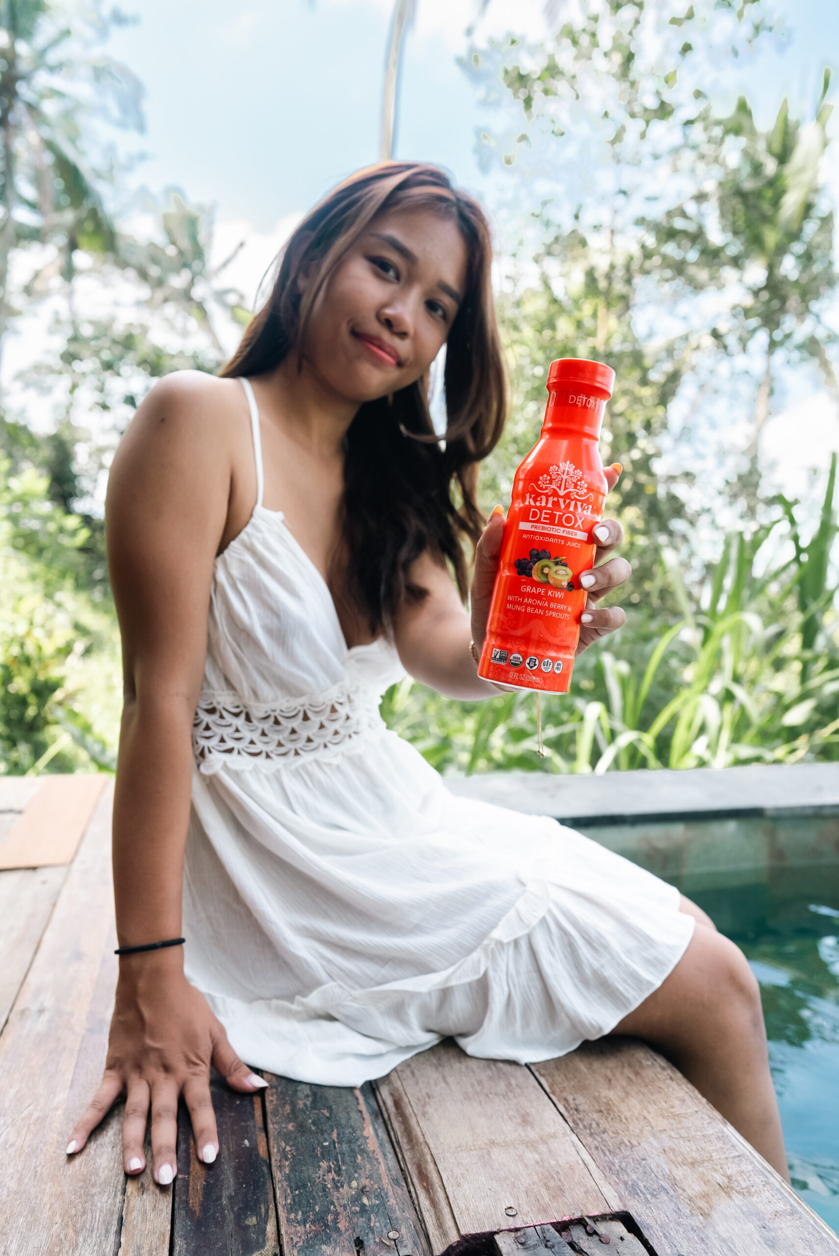 Woman holding red detox juice bottle outdoors