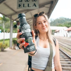 Woman holding KarViva Ace Sport drink at station
