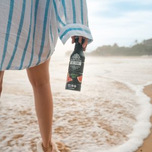 Person holding sports drink on beach shoreline