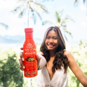 Woman holding red Karviva Detox juice bottle outdoors