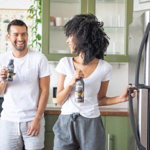 Smiling couple holding drinks in kitchen